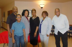 A group of people standing in front of a red chair.