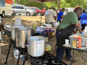 A group of people standing around a large pot.