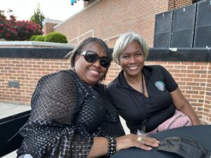 Two women sitting on a bench smiling for the camera.